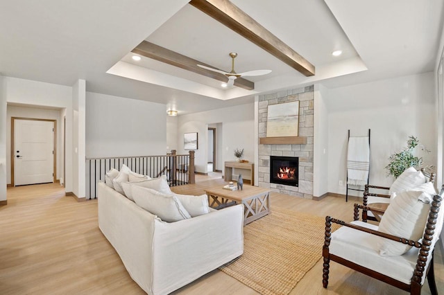 living area with ceiling fan, baseboards, a tray ceiling, recessed lighting, and light wood-style floors