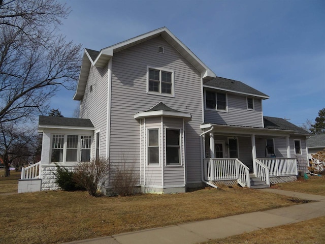 traditional-style house featuring a porch and a front yard