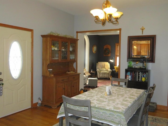 dining area with light wood finished floors, a notable chandelier, arched walkways, and baseboards