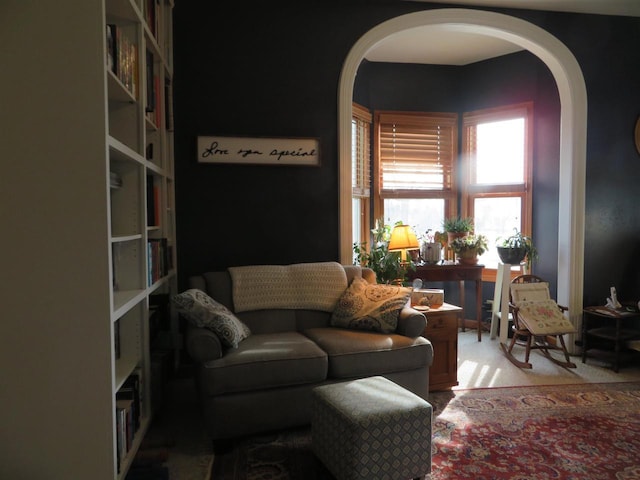 living area featuring arched walkways and light carpet