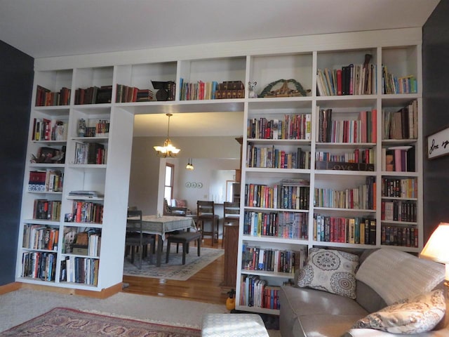 living area featuring a notable chandelier and wall of books