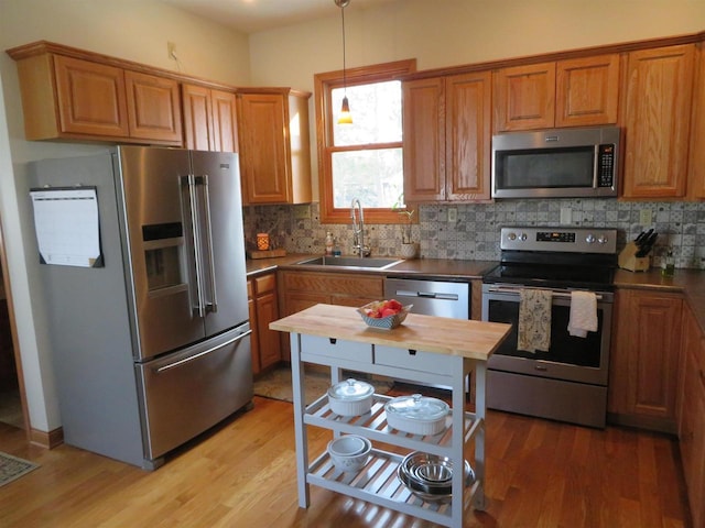 kitchen featuring decorative backsplash, light wood-style flooring, appliances with stainless steel finishes, and a sink