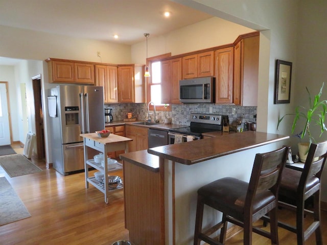 kitchen with decorative backsplash, a peninsula, appliances with stainless steel finishes, and a sink