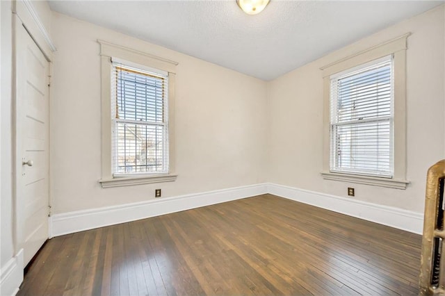 spare room with baseboards, a textured ceiling, and dark wood-style flooring