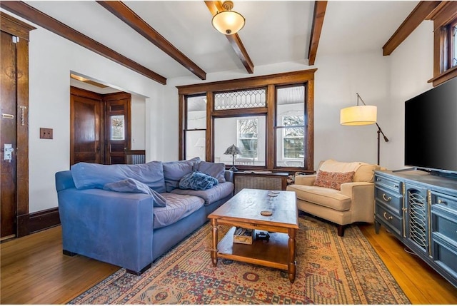 living area with beamed ceiling and wood finished floors