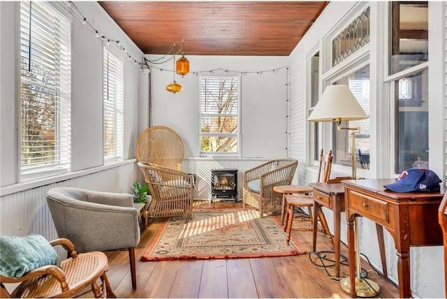 living area featuring wood ceiling, wood finished floors, and a wood stove