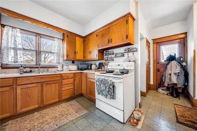 kitchen featuring electric range, brown cabinets, light countertops, and a sink