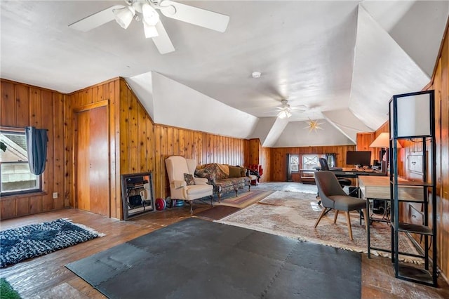 interior space with lofted ceiling, wooden walls, wood finished floors, and a ceiling fan