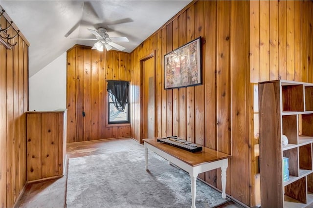 interior space with lofted ceiling, wooden walls, and ceiling fan