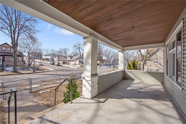 view of patio featuring a residential view, a porch, and fence