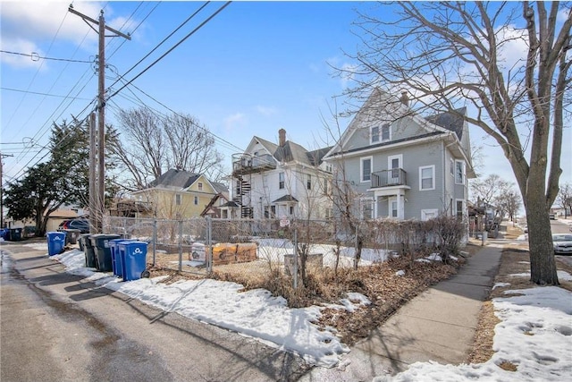 view of snowy exterior with a fenced front yard and a residential view