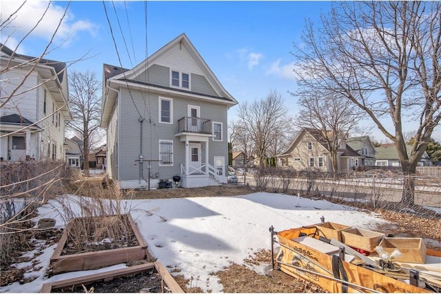 snow covered property featuring a balcony, a garden, fence, and a residential view