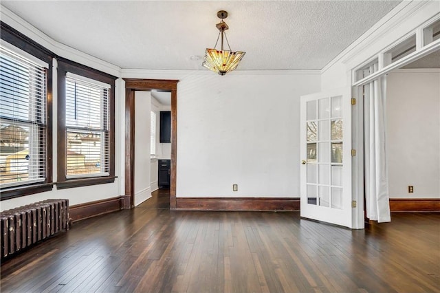 unfurnished dining area with hardwood / wood-style flooring, ornamental molding, radiator heating unit, and a textured ceiling