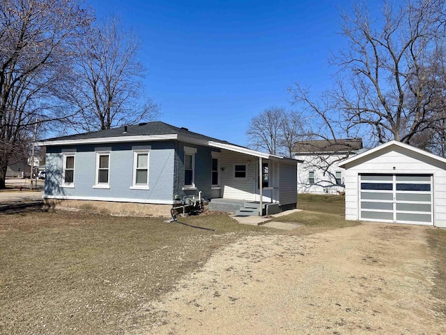 view of front of home featuring brick siding, a porch, a garage, an outbuilding, and driveway