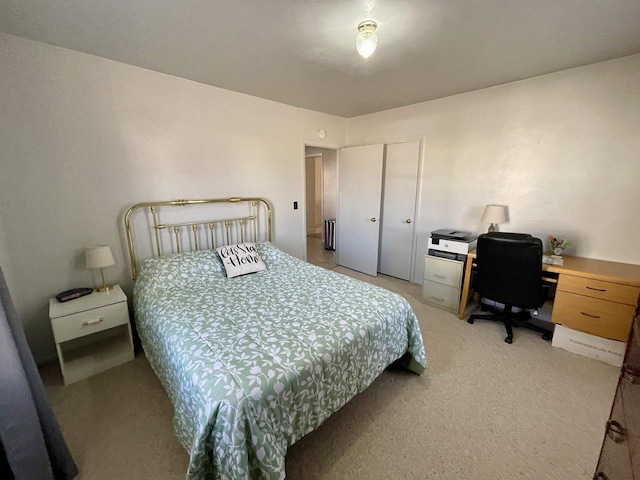 bedroom with a closet, light carpet, and radiator heating unit