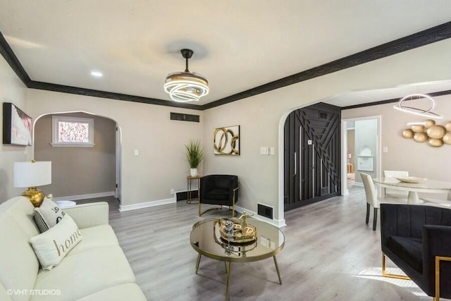 living area featuring visible vents, arched walkways, baseboards, and wood finished floors