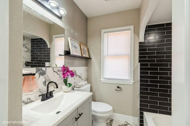 full bathroom featuring marble finish floor, toilet, vanity, and a healthy amount of sunlight