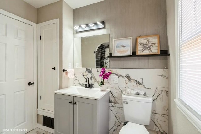 half bathroom with visible vents, toilet, marble finish floor, and vanity