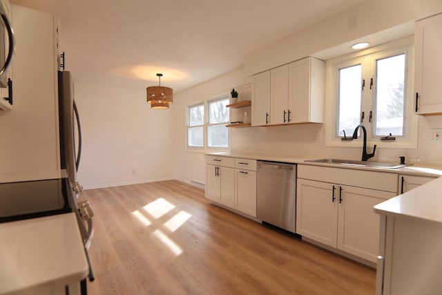 kitchen featuring light wood-style flooring, a sink, stainless steel dishwasher, white cabinets, and light countertops