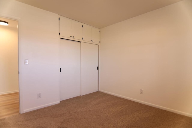 unfurnished bedroom with light carpet, baseboards, and a closet