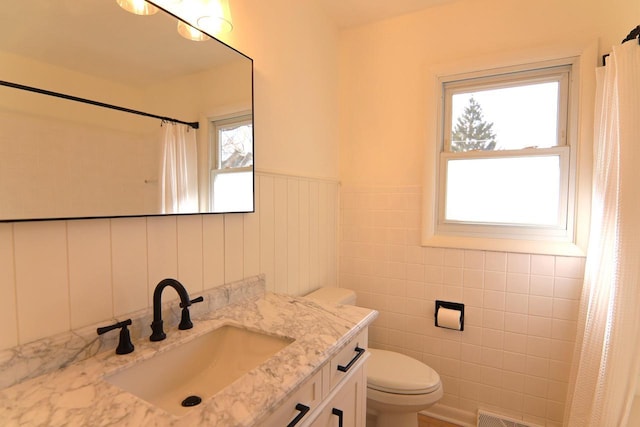 full bathroom with vanity, a shower with curtain, visible vents, wainscoting, and toilet