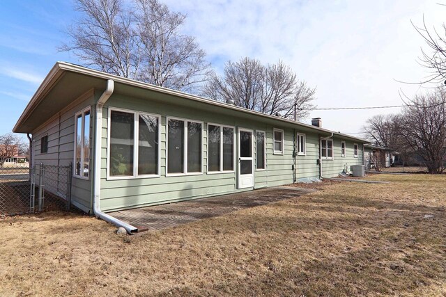 view of side of home with cooling unit, a lawn, and fence