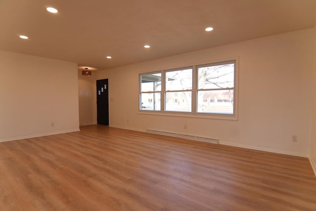 spare room featuring baseboard heating, recessed lighting, baseboards, and light wood-style floors