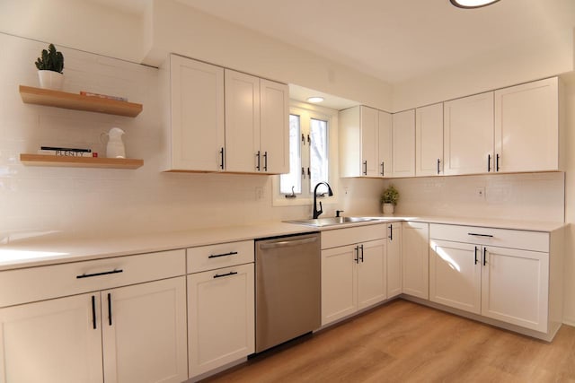 kitchen featuring a sink, dishwasher, light wood-style flooring, and white cabinetry