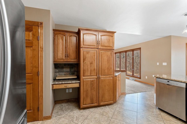 kitchen with light stone countertops, visible vents, light tile patterned flooring, stainless steel appliances, and brown cabinets