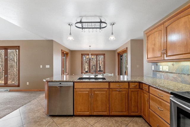 kitchen with backsplash, light stone countertops, appliances with stainless steel finishes, brown cabinetry, and a sink