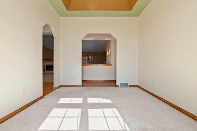 empty room featuring a tiled fireplace, carpet flooring, baseboards, and visible vents