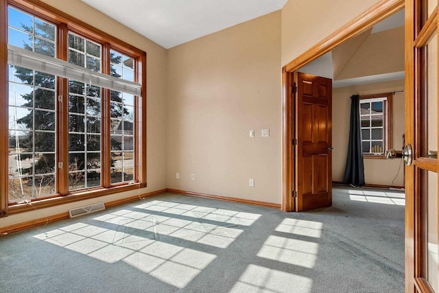 unfurnished room with visible vents, baseboards, light colored carpet, and lofted ceiling