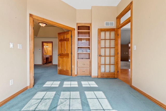 carpeted empty room featuring visible vents, baseboards, and built in features