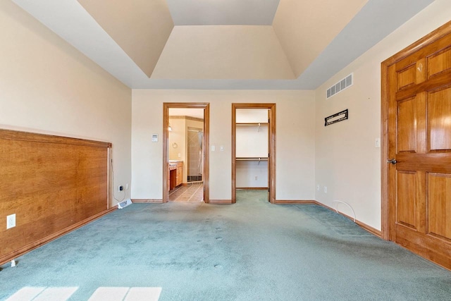 unfurnished bedroom featuring baseboards, visible vents, carpet floors, a tray ceiling, and ensuite bathroom