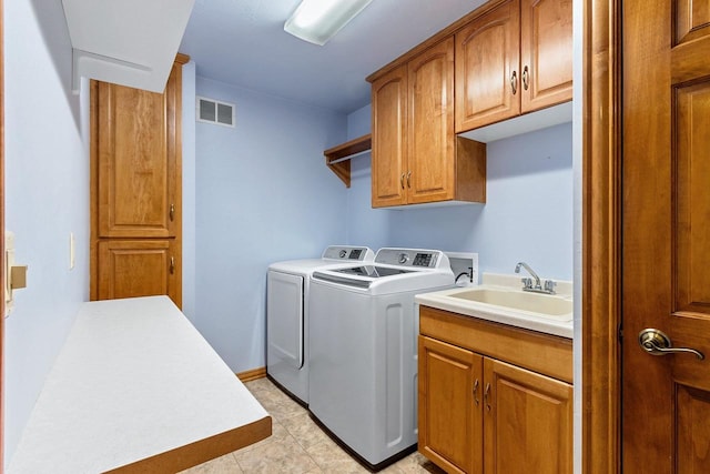 washroom with visible vents, washer and clothes dryer, a sink, cabinet space, and baseboards