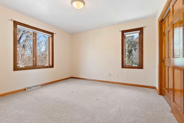 unfurnished room with light carpet, visible vents, and baseboards