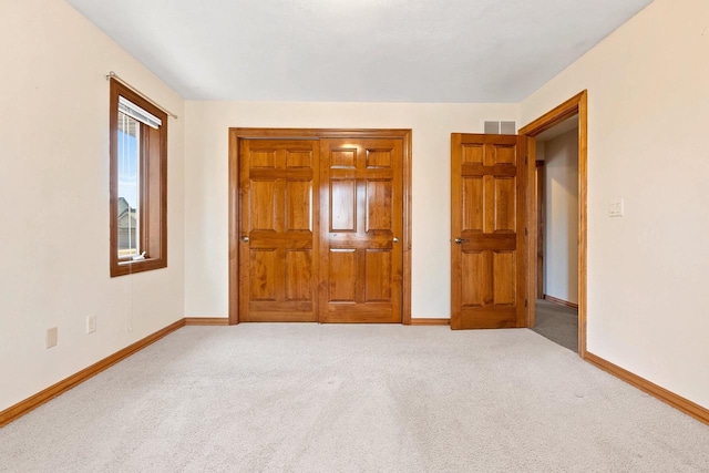 unfurnished bedroom featuring carpet, visible vents, a closet, and baseboards