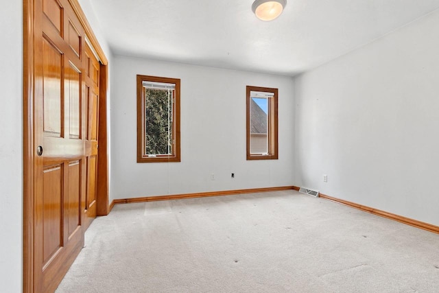 spare room with baseboards, visible vents, and light carpet