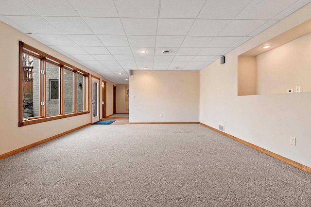 carpeted empty room featuring visible vents, a paneled ceiling, and baseboards