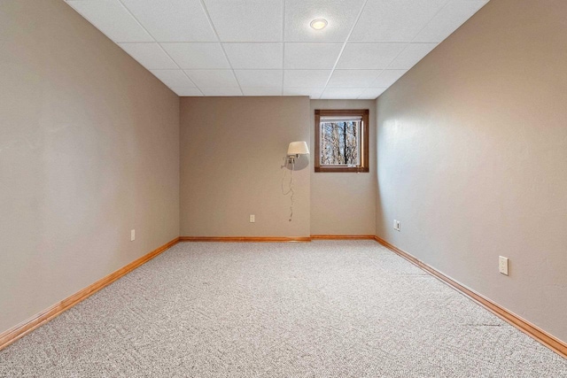 spare room with light carpet, a drop ceiling, and baseboards