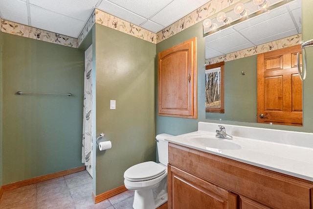 bathroom featuring tile patterned floors, toilet, baseboards, a paneled ceiling, and vanity