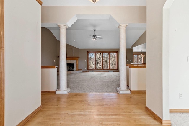 entrance foyer featuring decorative columns, light wood-style floors, a tile fireplace, and ceiling fan