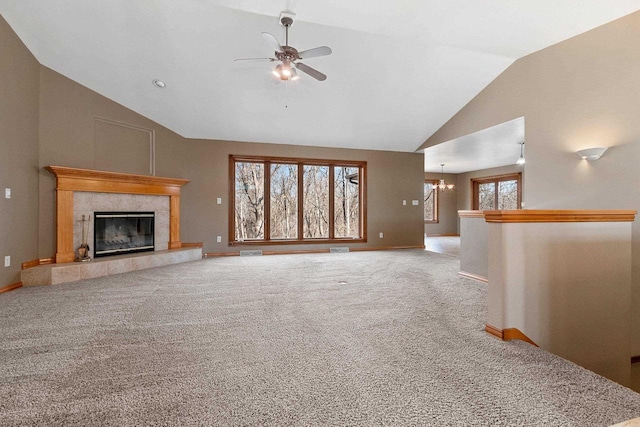 unfurnished living room featuring a tiled fireplace, ceiling fan with notable chandelier, carpet flooring, baseboards, and vaulted ceiling