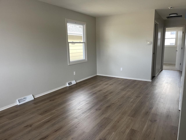 unfurnished room with dark wood finished floors and visible vents