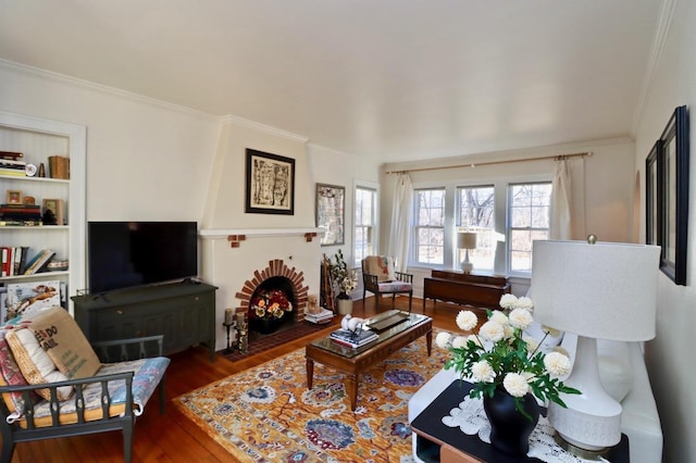 living area featuring a fireplace, crown molding, and wood finished floors