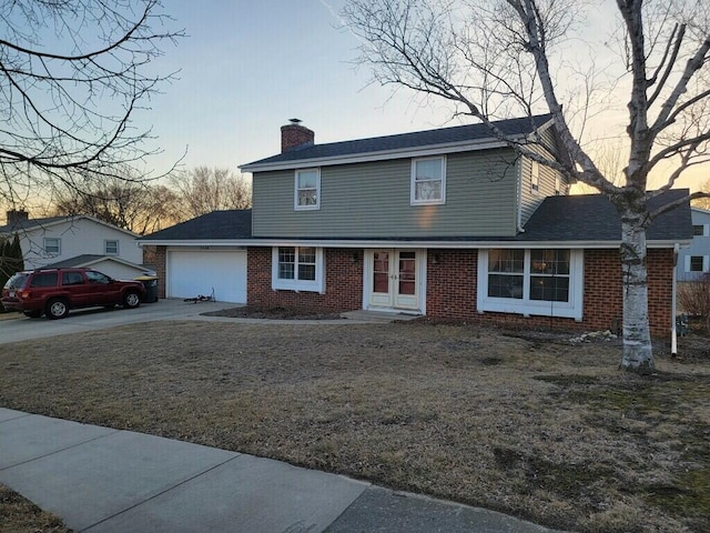 traditional-style house featuring roof with shingles, concrete driveway, a garage, brick siding, and a chimney