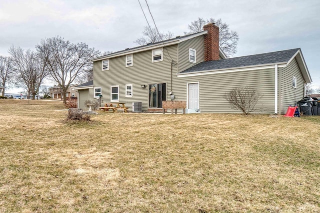 back of property with central AC unit, a lawn, and a chimney