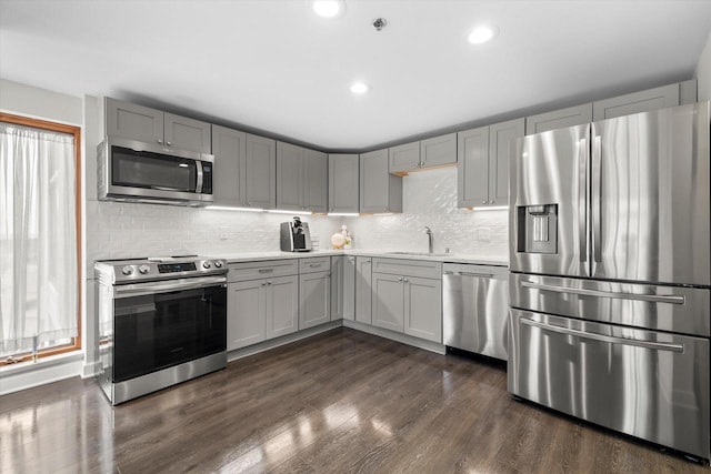 kitchen featuring dark wood-type flooring, gray cabinets, a sink, appliances with stainless steel finishes, and light countertops