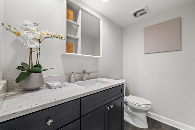 bathroom featuring vanity, wood finished floors, visible vents, baseboards, and toilet