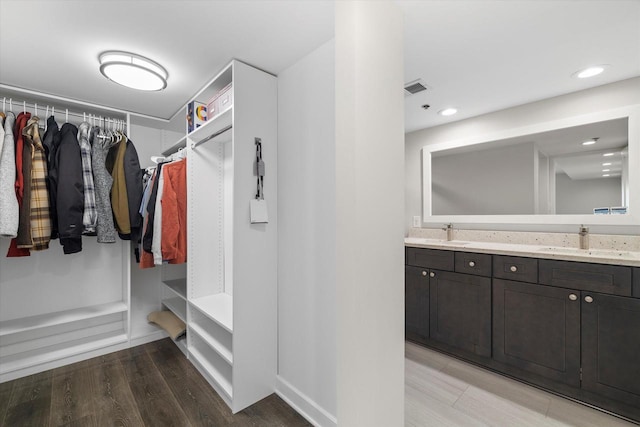 spacious closet featuring light wood-style floors, visible vents, and a sink